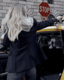 a woman is pointing a gun at a red stop sign