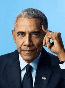 barack obama is wearing a suit and tie and touching his forehead with his finger .