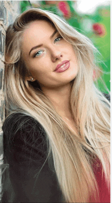 a woman with long blonde hair is leaning against a brick wall