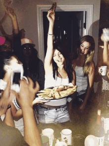 a group of people are gathered around a table with a woman holding a plate of food in her hand