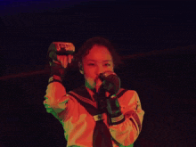 a woman is singing into a microphone in a dark room with red lights