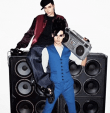 a man in a blue vest is holding a boombox while standing next to another man