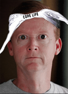 a man wearing a bandana with cope life on it