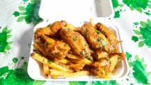 a container of chicken wings and french fries on a table