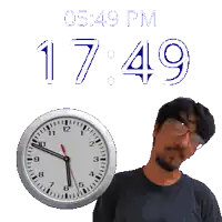 a man with glasses stands in front of a clock that says 17:49