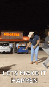 a man in a cowboy hat is dancing in a parking lot in front of a hooters restaurant .