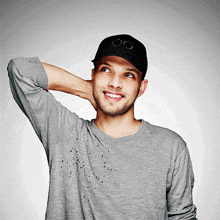 a man wearing a grey shirt and a black hat with the letters og on it