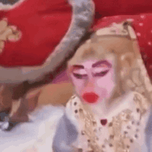 a monkey with a pink face and red lips is sitting on a bed .