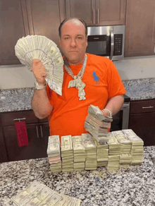 a man wearing an orange polo shirt holds up a fan of money