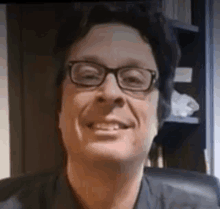 a man wearing glasses is smiling at the camera .