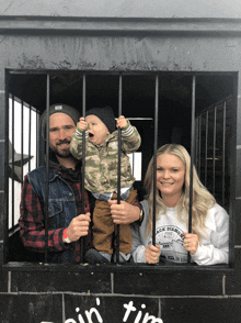 a man and woman holding a baby in a cage with a sign that says ' ain ' tim ' on it