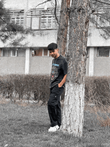 a young man leaning against a tree wearing a t-shirt that says static