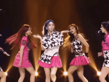 a group of girls are dancing on a stage and one of them is wearing a pink skirt