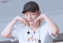 a man wearing a hat and earphones is making a heart shape with his hands .