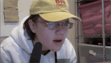 a woman wearing glasses and a yellow hat that says dig cheese