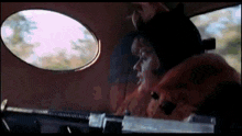 a woman in a fur coat is driving a car with a gun .