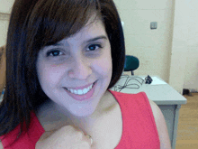 a woman wearing a red tank top smiles with a ring on her neck