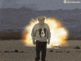 a man with a dog on his sweater is standing in front of an explosion