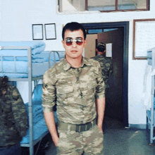 a man in a military uniform and sunglasses stands in a room with bunk beds