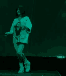 a woman is dancing on a stage in front of a green background .