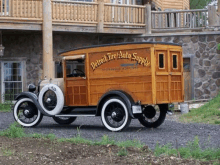 a wooden detroit tire auto supply truck parked in front of a stone building