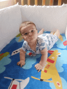 a baby is crawling on a blanket with an airplane on it