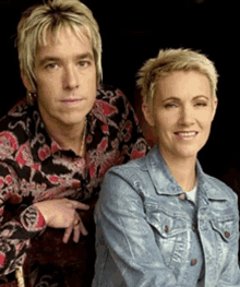 a man and a woman are posing for a picture and the woman is wearing a denim jacket with the word denim on the front