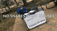 a man sitting at a table with a sign that says change my mind