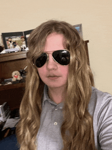 a person with long hair wearing sunglasses and a grey shirt