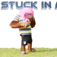 a monkey wearing a pink wig is standing in the grass with the words " stuck in " behind him