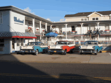 a row of old cars are parked in front of a white building that says motel