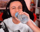 a man wearing headphones is drinking water from a bottle