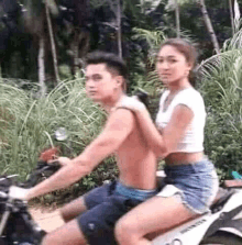 a man and a woman are riding a motorcycle on a dirt road .