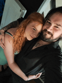 a man with a beard and a woman with red hair are posing for a photo