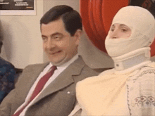 a man in a suit and tie is sitting next to a woman wearing a bandaged head .