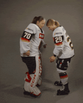 two female hockey players wearing jerseys that say penny