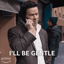 a man in a suit is talking on a cell phone with the words " i 'll be gentle " above him