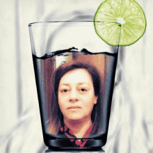 a woman 's face is in a glass of water with a slice of lime