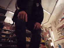 a man in a black jacket with a jd logo on it is kneeling down in a store