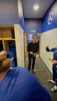 a group of men are standing in a locker room with a sign on the wall that says champions league