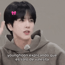 a younghoon is wearing a bow in his hair and a hoodie .