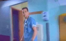 a man with a stethoscope around his neck is walking in a hospital hallway .