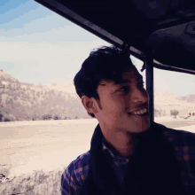 a man in a plaid shirt is smiling while looking out a window