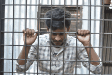 a young man in a plaid shirt behind bars