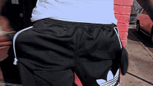 a person wearing black adidas shorts with white stripes on the side