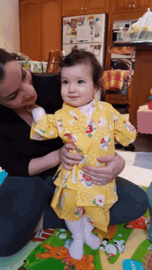 a woman is holding a baby in front of a refrigerator that has a picture of a rabbit on it