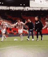 a group of soccer players are holding hands on a field with a man wearing a hoodie that says asics