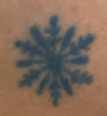 a close up of a blue snowflake tattoo on a person 's skin