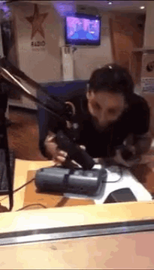 a man is sitting at a desk in front of a microphone in front of a sign that says radio