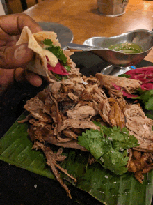 a person is holding a tortilla over a plate of food